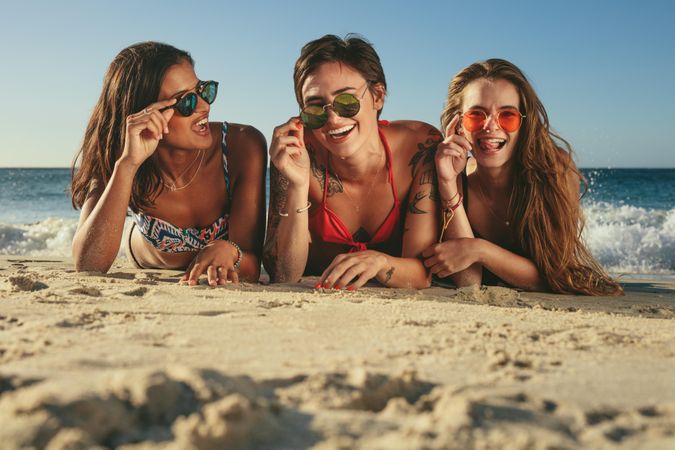 Beautiful women wearing fun sunglasses on sandy beach