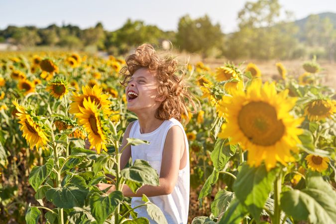 Boy laughing while standing in sunflower field