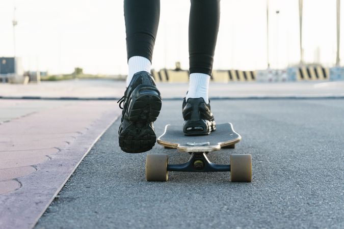 Feet of unrecognizable woman riding on longboard on the the street