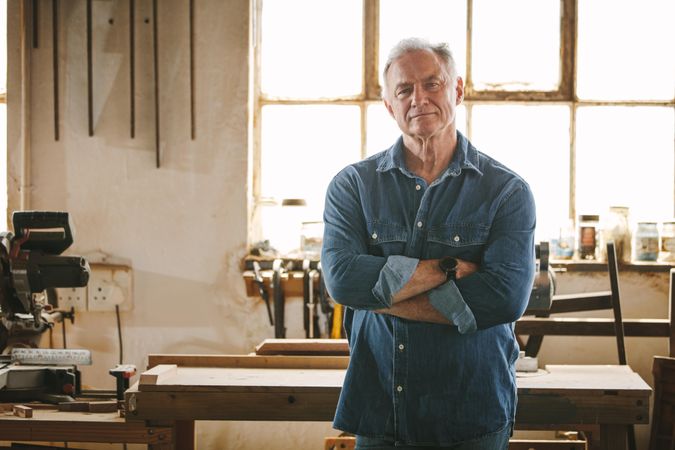 Mature man looking at camera while standing in workshop