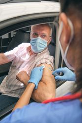Crop medic injecting vaccine into arm of mature driver