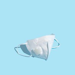 Medical mask on pastel blue background