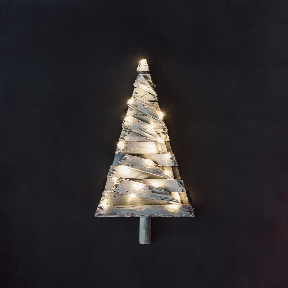 Christmas tree made of planks of wood with lights on dark background