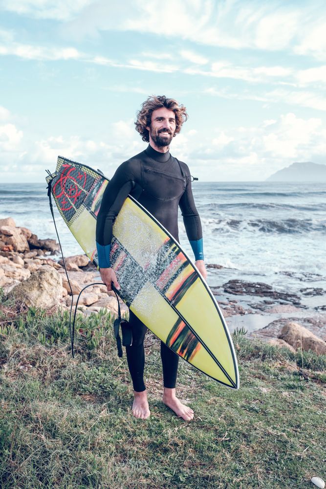 Smiling sportsman standing at seaside with surfboard