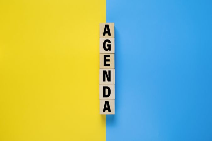 agenda word on wooden blocks isolated on yellow and blue background