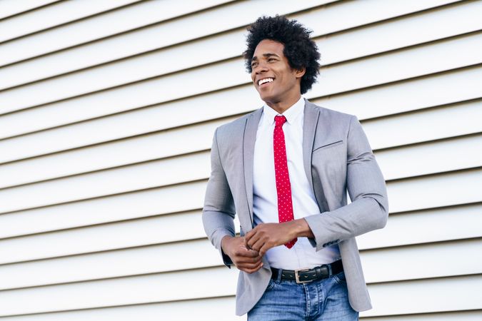 Man in jeans and dress shirt with tie smiling outside