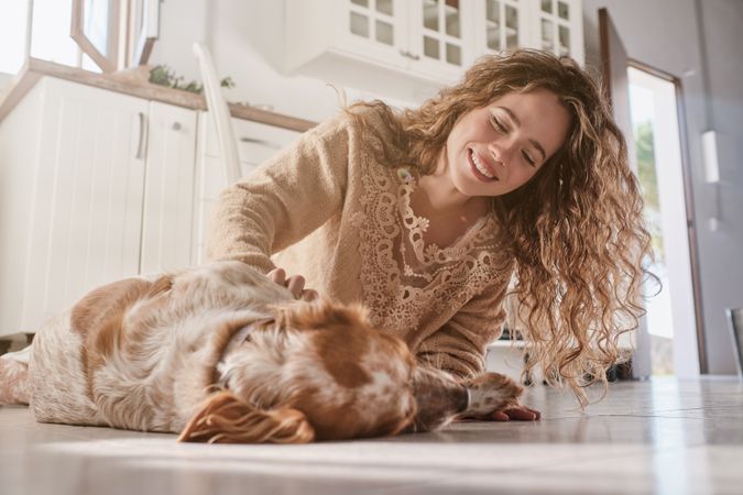 Joyful woman caressing dog on floor