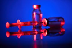 Syringe and vaccine ampoule in blue room