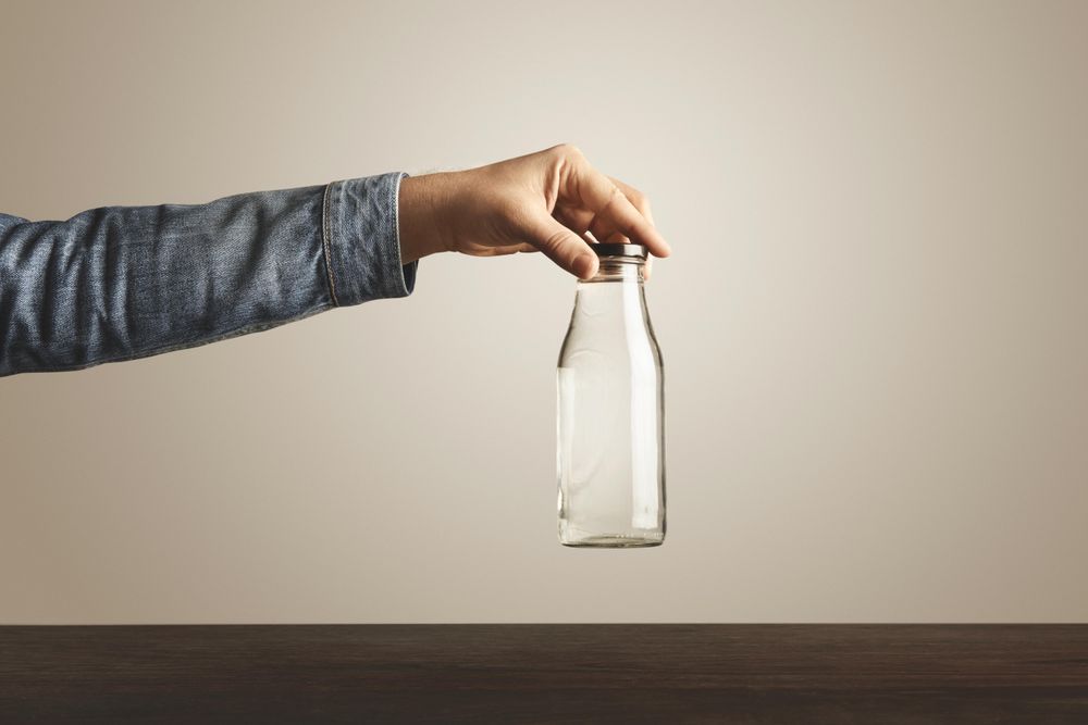 Arm holding glass water bottle