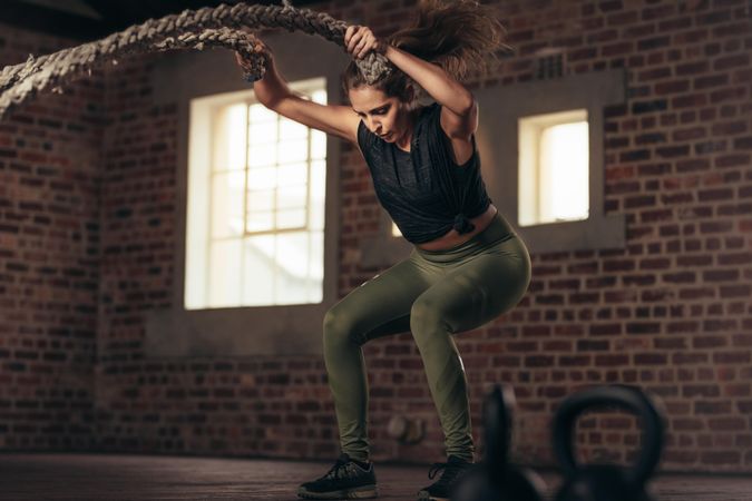 Fitness woman using training ropes for exercise at gym