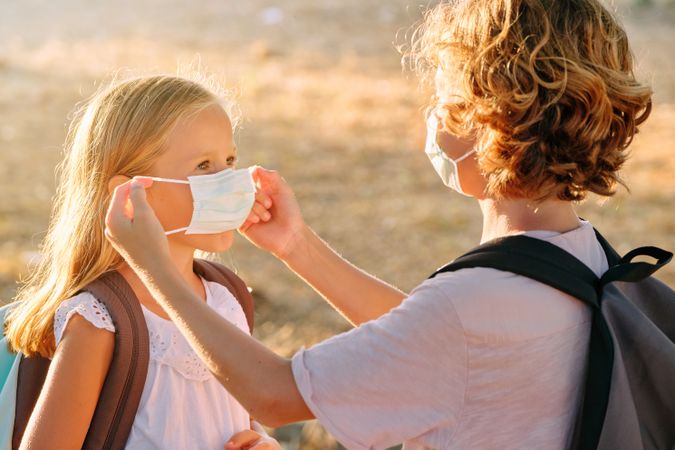 Brother putting safety mask on sister