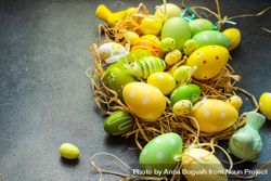 Colorful Easter decorations in straw on grey table 4NENxD