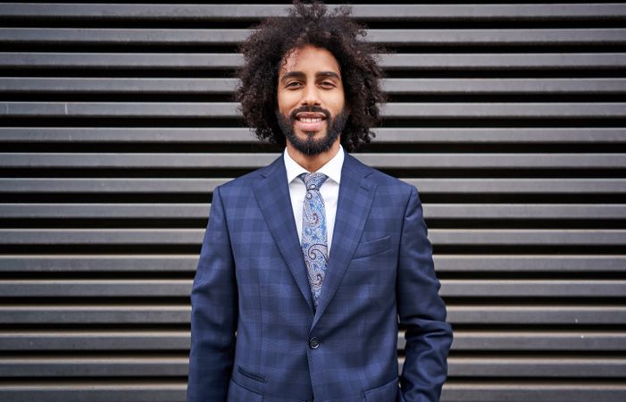 Presentable Black man standing near striped wall
