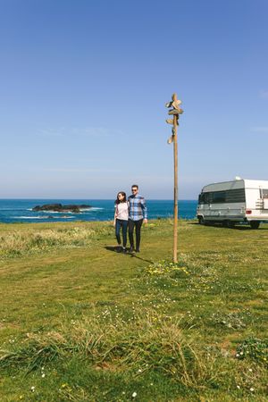 Couple taking a walk near the coast with a camper