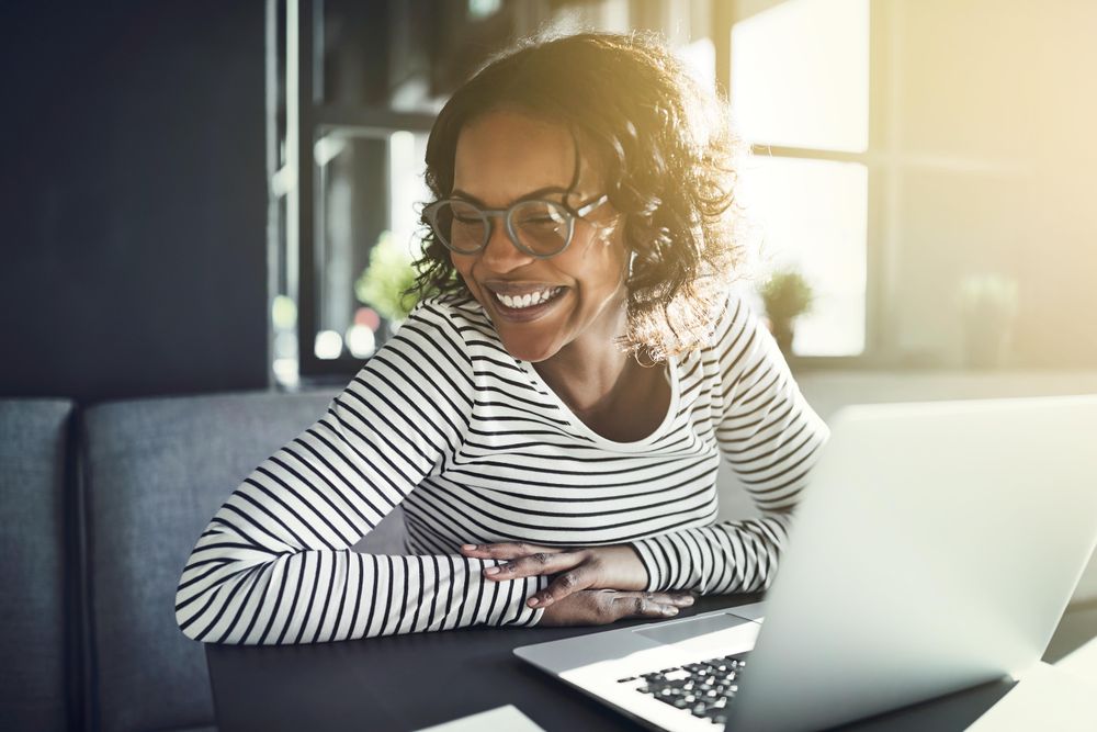 Happy woman sitting with laptop in cafe