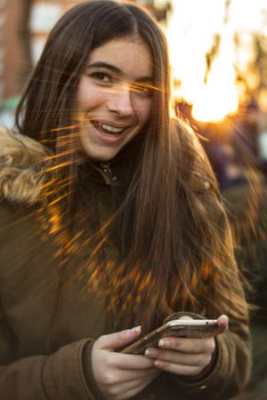 Cheerful female with smartphone on street