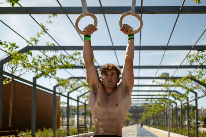 Strong young sportsman exercising with rings