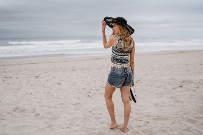 Young female walking barefoot on sandy beach