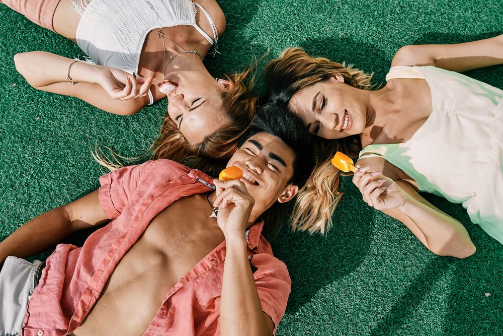 a group of young people having a good time and eating ice-cream lying on grass