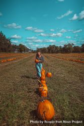 Girl in field holding pumpkin in pumpkin patch farm 0gRzlb