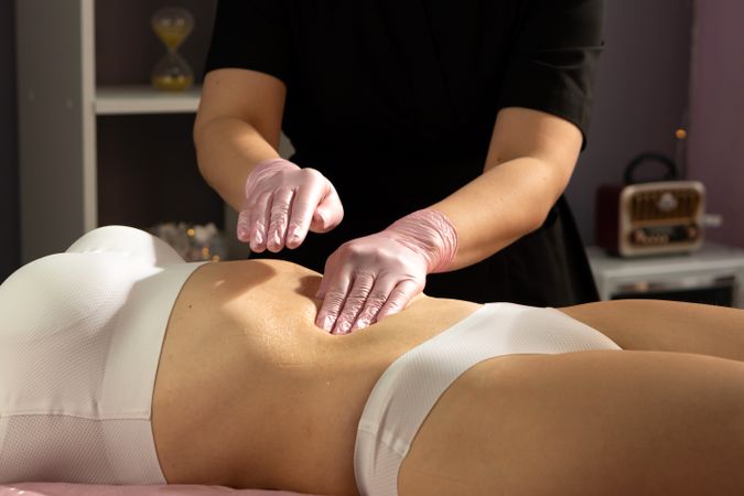 Gloved hands gently massage abdomen after honey application.