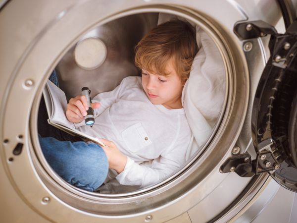Attentive boy reading book in washing machine