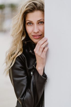 Charming tender woman standing behind white wall