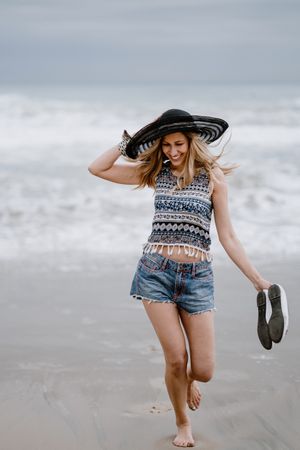 Young female walking barefoot on sandy beach