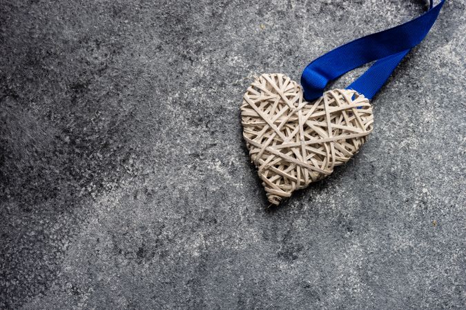 Thatched heart ornament with blue ribbon on grey counter