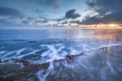 Sun rising over waving sea