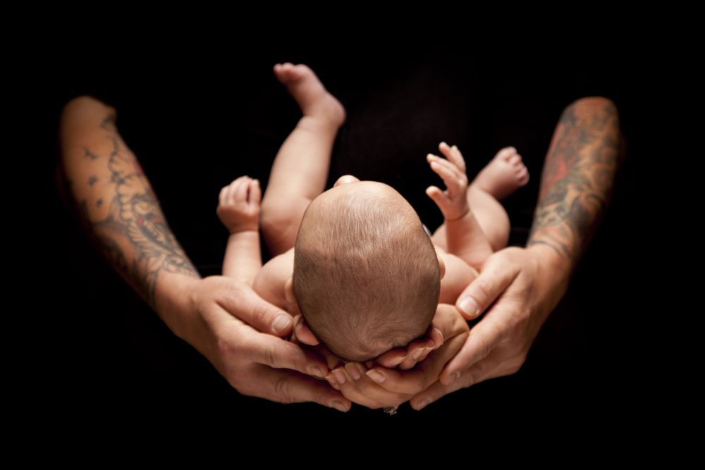 Hands of Father and Mother Hold Newborn Baby