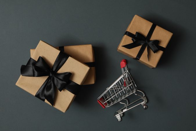 Gift boxes and shop trolley on gray background
