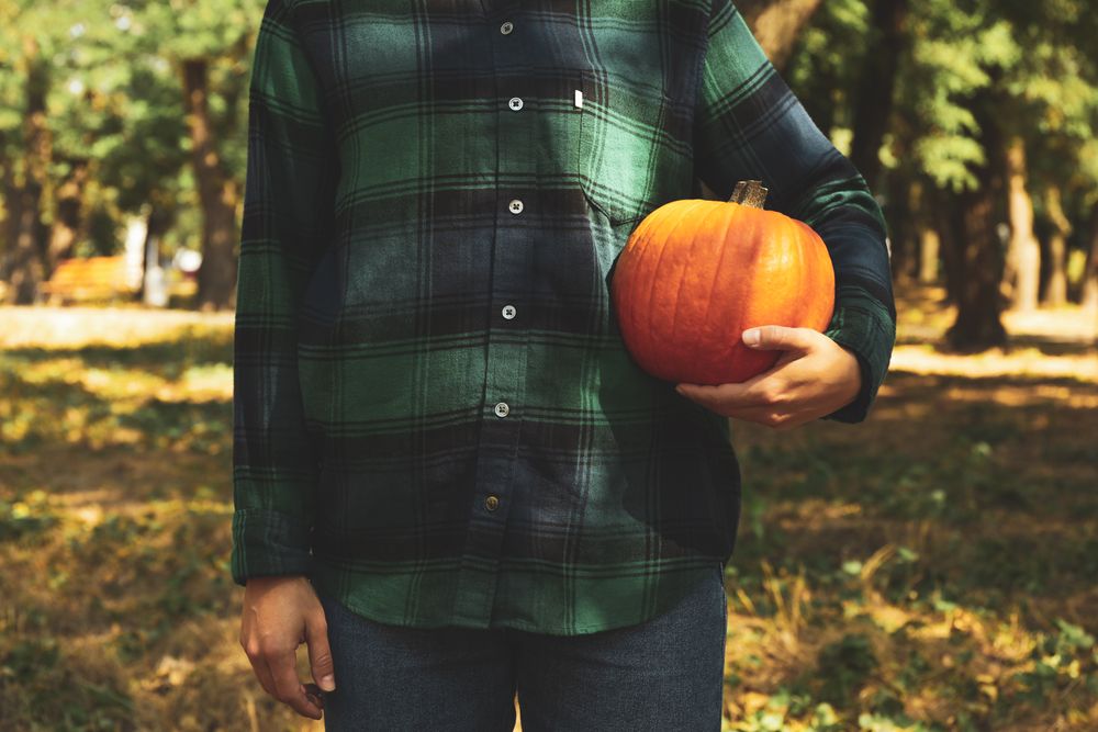 Woman in shirt and jeans hold pumpkin outdoor