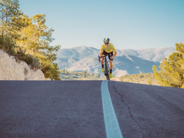 healthy man riding a bicycle on a mountain road in a sunny day