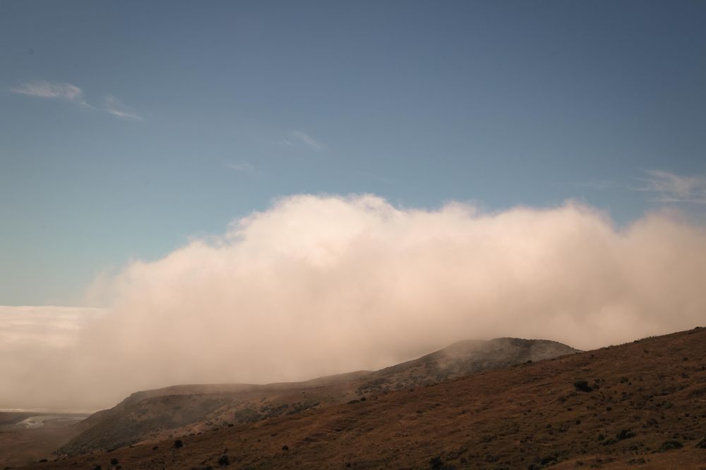 Blue sky with clouds rolling into the mountains
