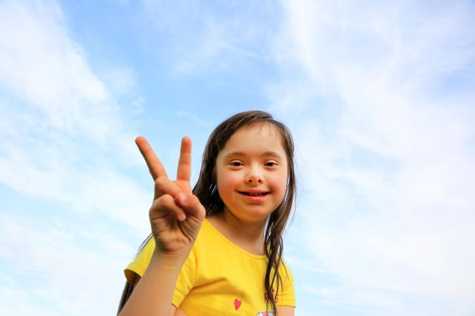 Young girl with Down syndrome making the peace sign