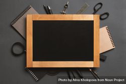 Framed writing board surrounded by stationary on dark background 5zvQg5