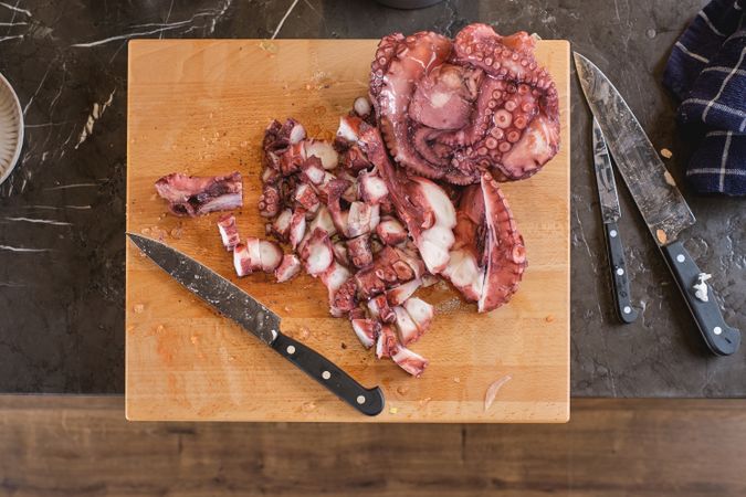 Raw octopus on cutting board with knife