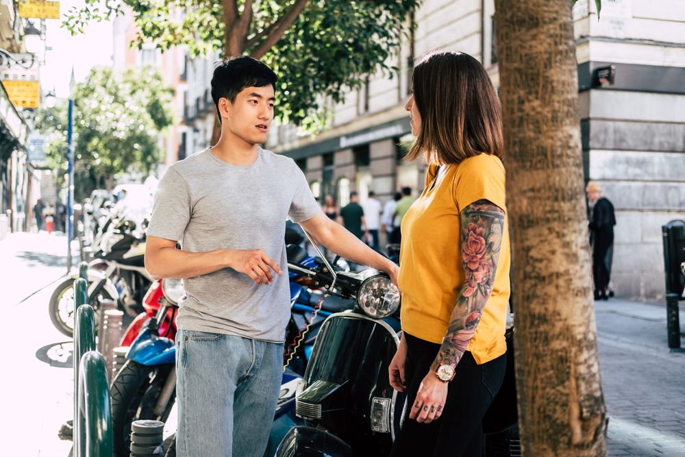 Modern multiracial couple talking while standing on street