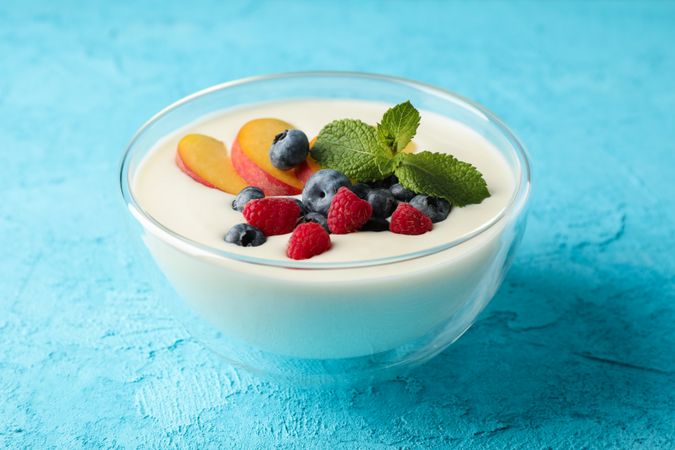 Bowl with sour cream yogurt and fruits on color background