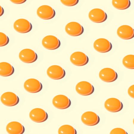 Egg yolk rows in pattern on pastel yellow background