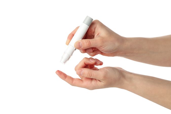 Female checking blood sugar level, isolated on light background