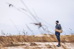 Man walking between sand field with dry grass