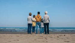Unrecognizable people in the beach backwards watching the sea