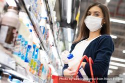 Woman picking up milk at grocery shopping in surgical mask 5lnjeb