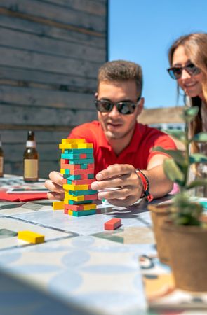 Concentrated man catching game piece next to colleague on terrace