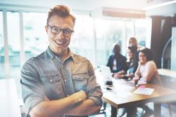 Smiling man in glasses pictured in front of his colleagues