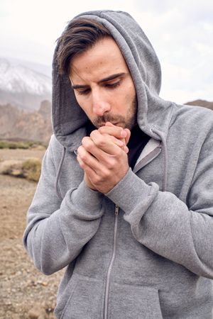 Serious man warming hands in mountains