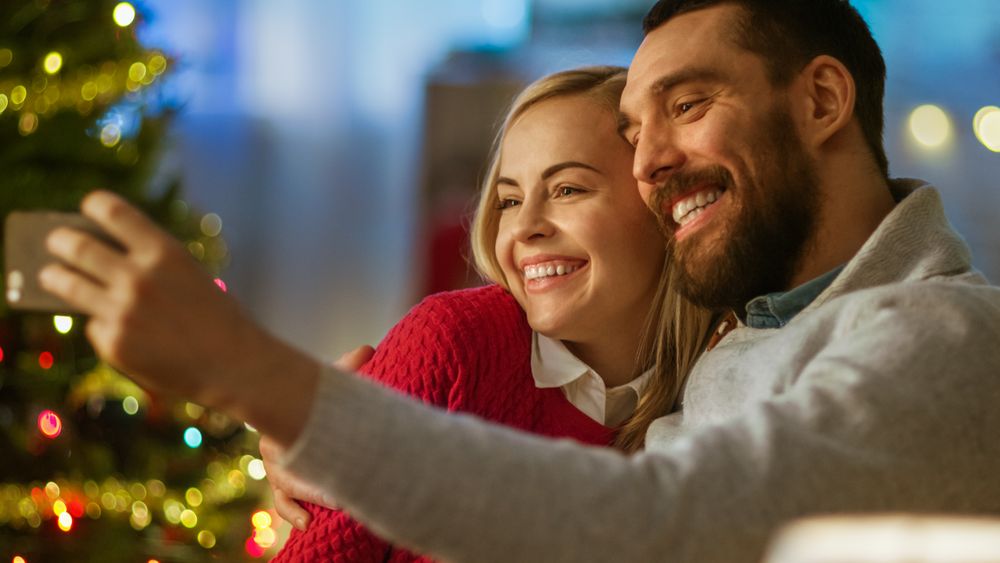 Man and Woman Sitting on the Couch Taking a Selfie with Smartphone, Smiling.