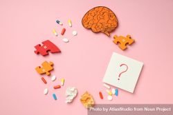 Pink paper with circle of pills, puzzle pieces, brain and question mark with copy space 4mrmWb